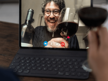 man on video chat with glass of red wine